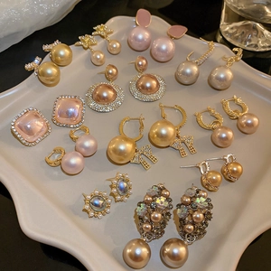 Flat lay of multiple pearl and zircon earrings in gold and pink on a beige tray