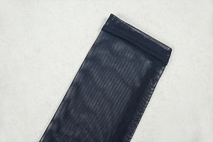 Detail shot of sheer pleated mesh fabric with precise stitching on high-quality dark fabric