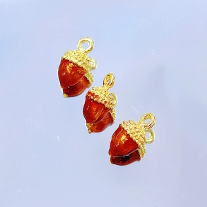 Detailed view of three acorn-shaped enamel pendants with textured gold metal caps