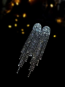 Macro shot of silver tassel earrings with sparkling rhinestones on a dark background