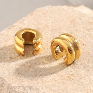 Macro shot of 18K gold plated double-layer C-shape ear cuffs on a textured stone surface