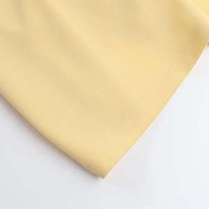 Detail of light yellow fabric featuring high-quality white stitching and compact texture