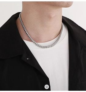 Close-up of a men's silver stainless steel Cuban link chain necklace worn by a model