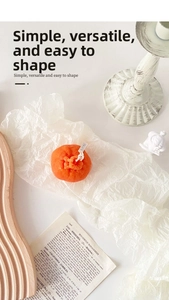 Macro detail of orange-shaped candle with realistic texture on pleated white paper