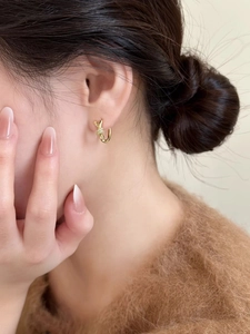 Gros plan sur une boucle d'oreille nœud dorée avec oxydes de zirconium sur modèle