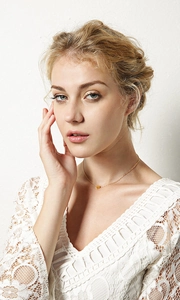 Delicate gold heart pendant necklace on minimalist chain worn with a white lace top