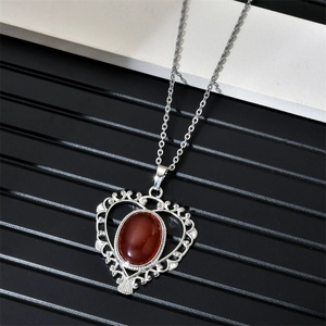 Gros plan du collier cœur avec pierre précieuse brun rouge et bordure filigranée argent