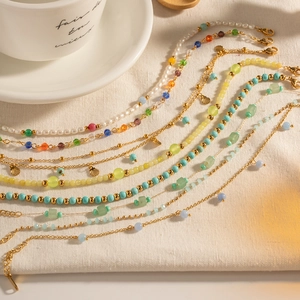 Bohemian colorful beaded and pearl layered anklets with golden chains on beige linen