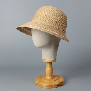 Detailed close-up of beige raffia sun hat with elegant woven texture and white ribbon trim