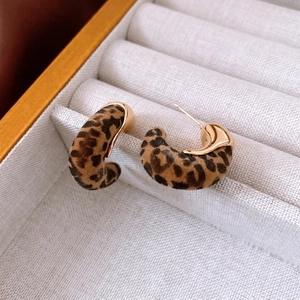 Boucles d'oreilles créoles léopard plaquées or 18K sur boîte à bijoux beige en velours