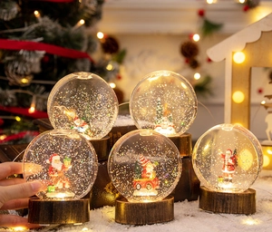 Détail de boules de cristal de Noël lumineuses avec socle en bois et lumière chaude