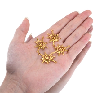Golden stainless steel sun charms with swirl center design held in hand for size comparison