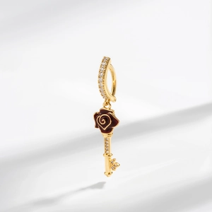 Detail of gold navel piercing with red enamel rose key pendant and clear crystals