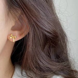 Elegant gold bow-shaped S925 sterling silver earrings with a polished mirror finish on model