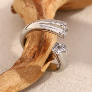 Macro shot of silver star-shaped open ring with zircon inlay on natural wood texture