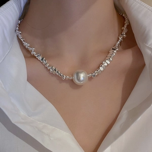 Close-up of irregular silver-tone beads and a large white pearl pendant on a model's neck
