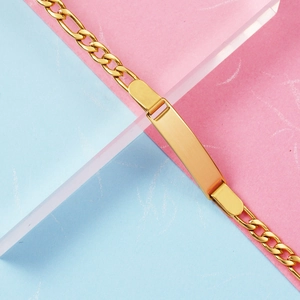 Detailed view of polished gold Figaro chain kids ID bracelet on aesthetic background