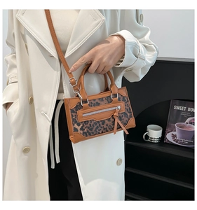 Detailed close-up of brown leopard print handbag with silver zippers and elegant hand straps