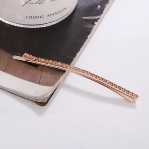 Close-up of a rose gold hair clip featuring rows of sparkling rhinestones on a magazine