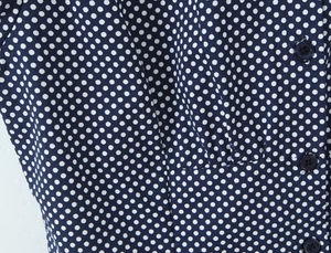 Detailed close-up of dark blue polka dot fabric texture and button closure on shirt