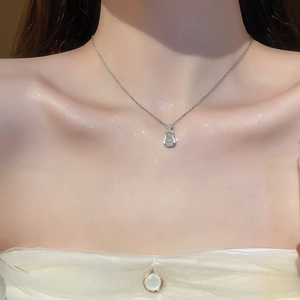 Gros plan d'un collier argenté avec pendentif gourde en opale blanche sur le cou d'un mannequin