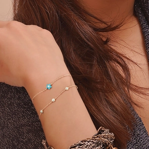 Detailed shot of two gold flower bracelets with blue floral and turquoise stone charms