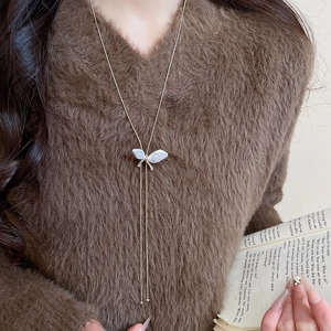 Detail of a butterfly pendant with pearls, diamonds and tassels on a gold sweater chain