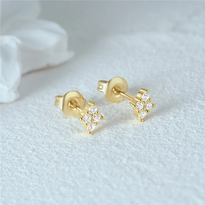 Detailed view of gold plated four-stone zircon stud earrings on a textured background