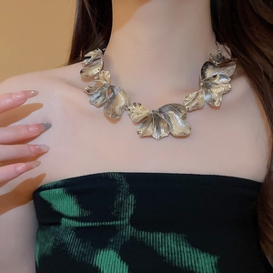 Macro detail of textured silver flower necklace with brushed metal petals and artistic design
