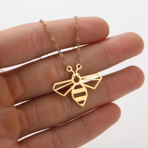 Minimalist hollow bee pendant necklace in gold finish held to show its vintage design