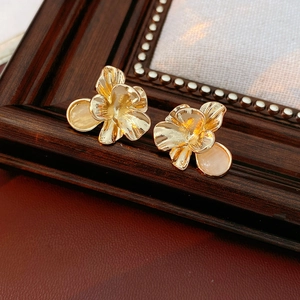 Detail of vintage gold floral earrings with brushed texture and champagne gemstone