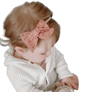 Pink soft nylon baby headband with hollow pattern on a girl in white cardigan