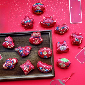 Flat lay of Chinese New Year plush charms with Maneki Neko and red fortune bags