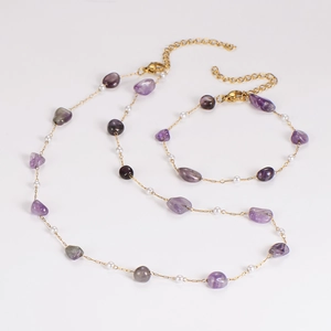 Detail of gold chain necklace and bracelet set with purple stones and pearls