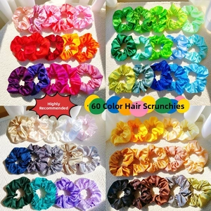 Macro display of 60 colors satin silk scrunchies on white textured background