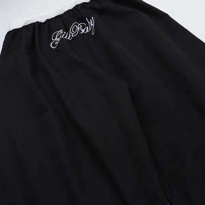 Détail du pantalon cargo noir avec bordure en dentelle blanche et broderie