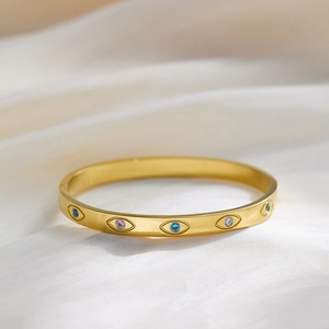 Elegant gold titanium steel bangle with colorful zircon evil eye charms on white silk