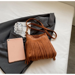 Detail of bohemian brown suede shoulder bag with white embroidery and long fringe tassels