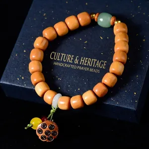 Détail d'un bracelet en bois avec pendentif lotus et perle de jade verte sur fond bleu