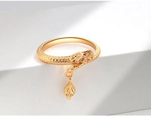 Detail of golden dragon ring with red gem eye and scale texture on white geometric stand