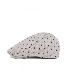 Detail view of grey herringbone newsboy cap featuring embroidered small red hearts on side