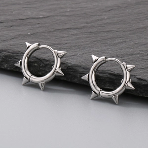 Close-up of silver stainless steel hoop earrings with punk rivets on a dark stone