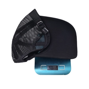 Solid black mesh baseball cap with long brim being weighed on a scale showing 96 grams