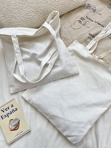 Minimalist off-white canvas tote bag featuring a zipper and large interior capacity