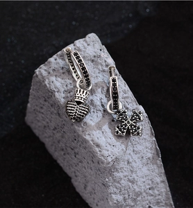 Detail of asymmetric hip-hop earrings with black zircon cross and crown heart pendant