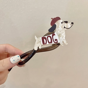 Détail d'une pince à cheveux chien crème avec béret rouge et texture marbrée