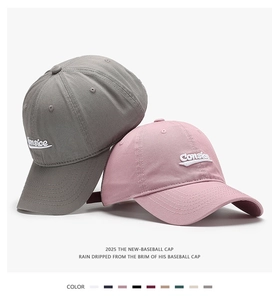 Close-up of pink and grey cotton baseball caps featuring side 3D letter embroidery