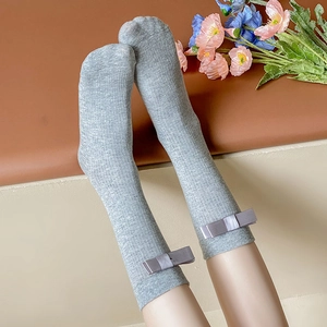 Gray ribbed mid-calf socks with decorative bows displayed on a model's legs