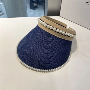 Detailed view of dark blue woven straw visor featuring elegant white pearl bead embellishments