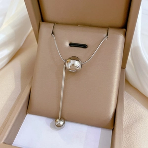 Detailed shot of silver tassel pendant necklace with round beads in a beige jewelry box